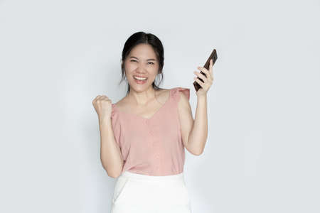 Asian beautiful woman is holding smartphone and smiling  with a happiness  for  shopping online or wining.の写真素材