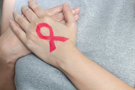 Asian woman are show Pink ribbon which draw by lip stick on back hand and touch breast to encourage...
