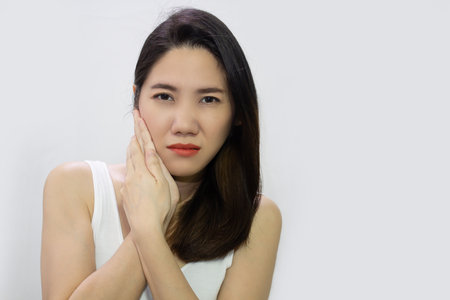 Asian beautiful woman touch her cheek and toothache and painful and have hyper sensitive teeth.の写真素材