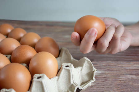 Woman's hand is pick up egg from paper packaging tray and holding it to preparing foods.の写真素材