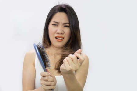 Asian beautiful woman are pulling  her hair loss on brush with a shocked and worry face.の写真素材