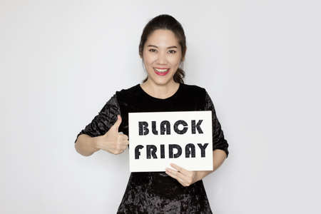 Asian beautiful woman holding black Friday paper ad and make thumbs up hand sign with smile and a happy.の写真素材