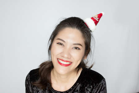 Asian beautiful woman wear small red merry X'mas hat with smiling and happiness to celebrating on Christmas and happy new yearの写真素材
