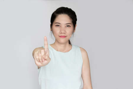 Asian beautiful woman raise indicated finger gesture hand sign to prohibit and warning peopleの写真素材