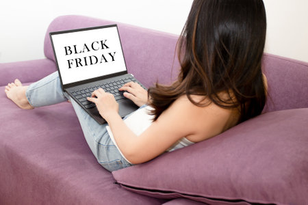 Asian beautiful woman sitting on sofa with laptop and typing search for Shopping online. a Black Friday shoppingの写真素材