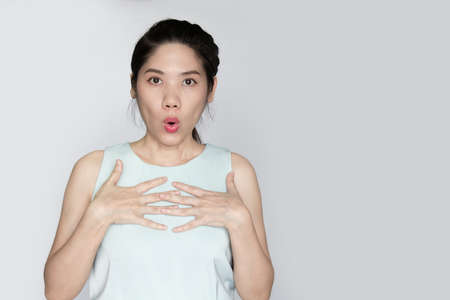 Asian beautiful women raise hand touch her chest with shocked and  surprised face when get good and bad news or information or a promotionの写真素材
