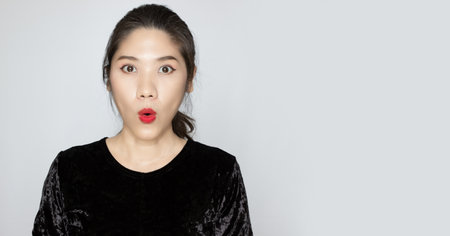 Asian beautiful woman is puckering lip with amazed, surpised, unbelievable face to know promotion sale or a newsの写真素材
