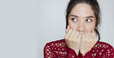 A Asian beautiful woman covering mouth and look away with fear and nervousの写真素材