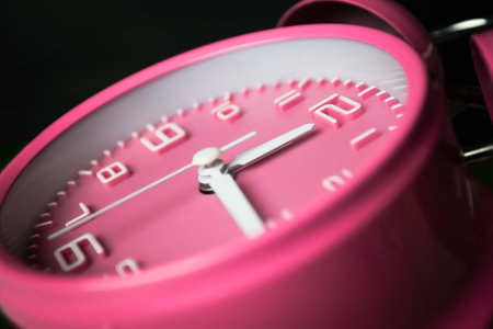 Pink alarm clock setting at noon or midnight. A Time conceptualの写真素材