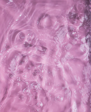 Closeup pink clear water surface texture with wave and splashes and bubbles. A Summer nature background.の写真素材