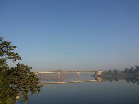 Reflection of bridge over calm river waterの素材