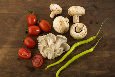 Vegetable: Top View of Oyster and Button Mushrooms with Red Baby Tomatoes Isolated on Brown Wooden Backgroundの写真素材