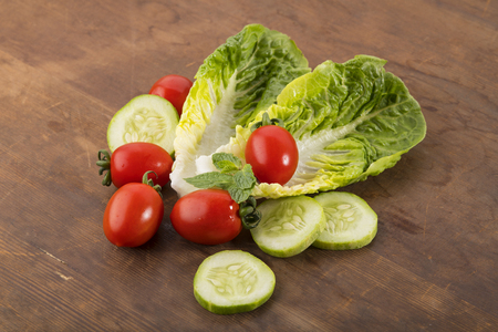 Vegetable: Fresh Green Romaine Lettuce with Baby Tomatoes, Mint Leaves and Cucumber Slices on Brown Wooden Backgroundの写真素材