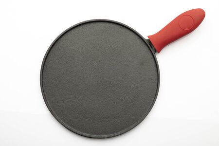 Top View of Seasoned Cast Iron Pan on White Background with Red Silicon Handle Gripの写真素材