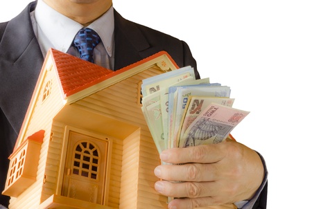 Businessman holding model house and banknotes, isolated on white backgroundの写真素材