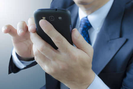 Businessman touching mobile phone , isolated on white backgroundの写真素材