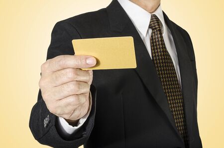 Businessman with credit card in hand isolated on yellow backgroundの写真素材
