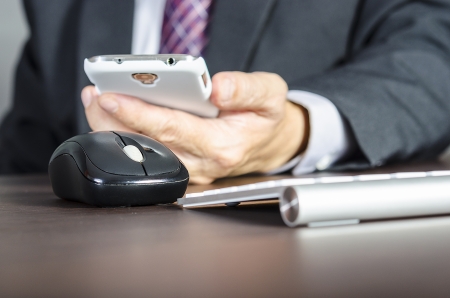 Businessman using mobile phone and computer ,focus on computer mouseの写真素材