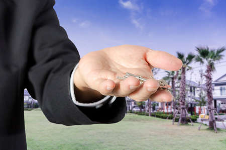 business man with house key in hand- real estate concept, isolated  backgroundの写真素材