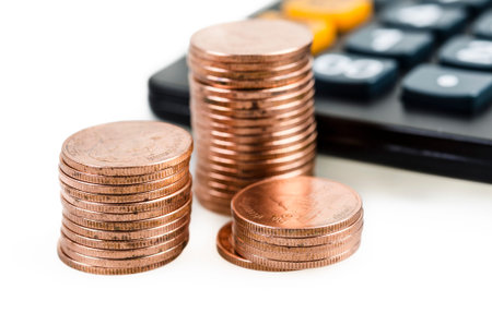 Stack of coins and calculator on white background