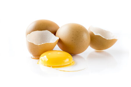Raw egg yolk with the cracked open egg shell , Isolated on white backgroundの写真素材