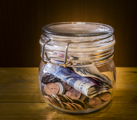 Money in jar on wooden tableの写真素材