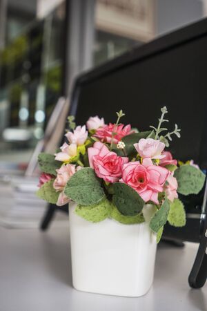 Artificial flower vase on table top over the desktop computerの写真素材