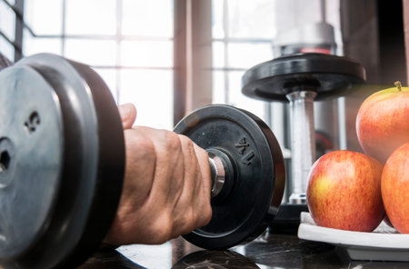 Hand holding dumbbell in fitness room : Concept for healthy