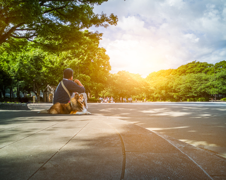 Man with dog sitting in the park in the morning.の写真素材