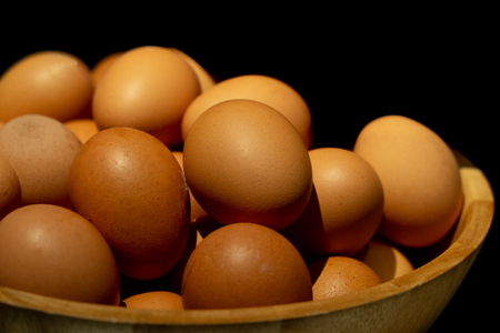 Close up of fresh checken eggs on wooden basket on black background prepare for breakfast.の写真素材