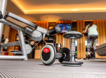Dumbbell in fitness room with blurred people exercise in backgroundの写真素材
