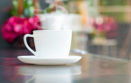 Steaming coffee cup with smoke on marble table in coffee shopの写真素材