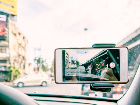Driving car in the city with mobile phone recording video of traffic