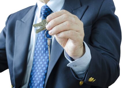 Businessman with house key in hand, isolated on white backgroundの写真素材