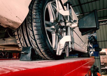 Tire clamped with lazer aligner undergoing auto wheel alignment in modern garage serviceの写真素材