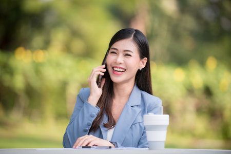 Business woman using tablet on lunch break in city park. Young professional businesswoman sitting at table at cafe.の写真素材