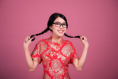 Action portrait beautiful Asian girl wearing Cheongsam red dress. the celebration of something in a...