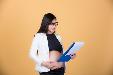 Beautiful pregnant woman portrait Asian woman isolated on yellow background. Facial expressions, feelings, emotions, body language, beauty and concept of rebirth, and motherhood readiness.の写真素材