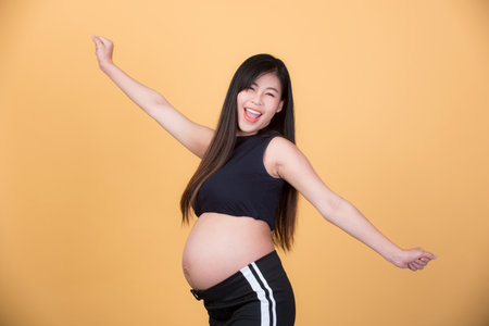 Beautiful pregnant woman, Asian drinking milk On a yellow background, the expectation of a young mother, pregnancy and childbirth pictures.の写真素材