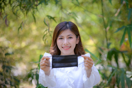 Portrait of an Asian woman wearing a black oil mask, anti-virus, or anti-Covid-19. Feeling stressedの写真素材