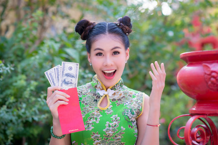 Action pictures of beautiful Asian girls wearing red cheongsam To celebrate something with a fun festival and shoppingの写真素材