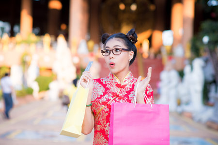 Action pictures of beautiful Asian girls wearing red cheongsam To celebrate something with a fun festival and shoppingの写真素材