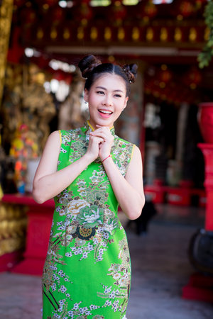 Action portrait beautiful Asian girl wearing Cheongsam green dress. the celebration of something in a joyful and exuberant way. Festivities and Celebration conceptの写真素材