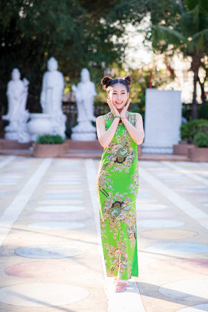 Action portrait beautiful Asian girl wearing Cheongsam green dress. the celebration of something in...