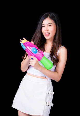 Portrait cheerful young asian woman Wearing a yellow tank top ,holding plastic water gun Smiling and having fun playing in the water Songkran festival, Songkran Thailand. isolated on black background.の写真素材