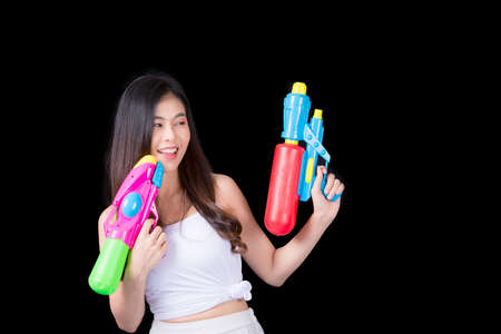 Portrait cheerful young asian woman Wearing a yellow tank top ,holding plastic water gun Smiling and having fun playing in the water Songkran festival, Songkran Thailand. isolated on black background.の写真素材