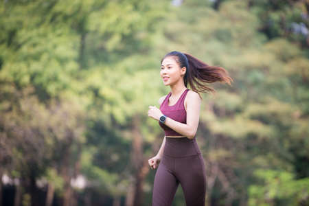 Asian Young female athlete jogging in forest. Jogger doing morning physical training.の写真素材