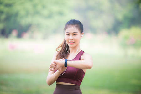 Asian female athletes smile and listen to music on a smartphone Relaxing in the parkの写真素材