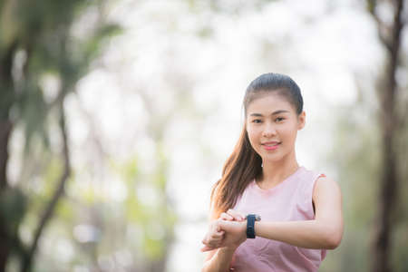 Asian female athletes smile and listen to music on a smartphone Relaxing in the parkの写真素材