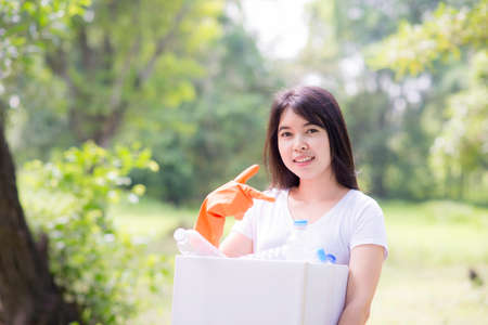Woman hand picking up garbage plastic and Glass bottles for cleaning at parkの写真素材